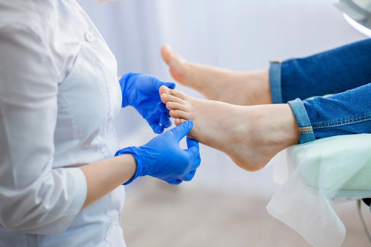 A healthcare professional in gloves examines a patient's foot during a podiatry consultation, ensuring proper care and assessment.